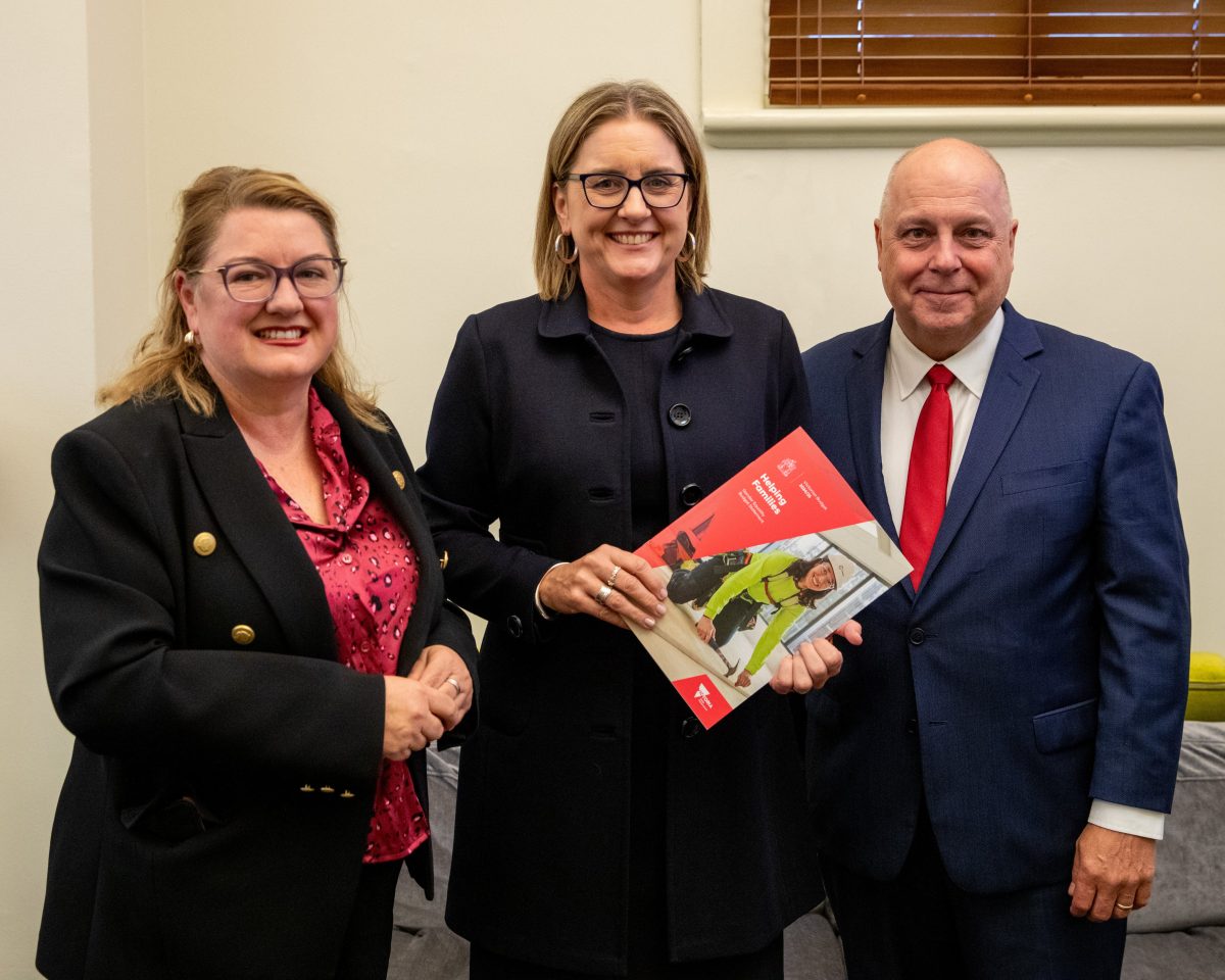 Natalie Hutchins, Jacinta Allan and Tim Pallas standing together with a copy of the 2024-25 State Budget.