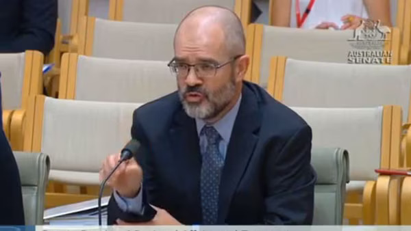 man speaking at government hearing or inquiry