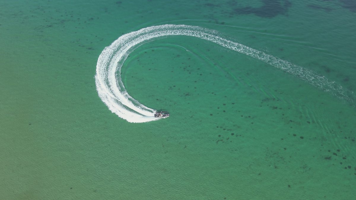 A bird's-eye view of a police boat doing a turn in the water