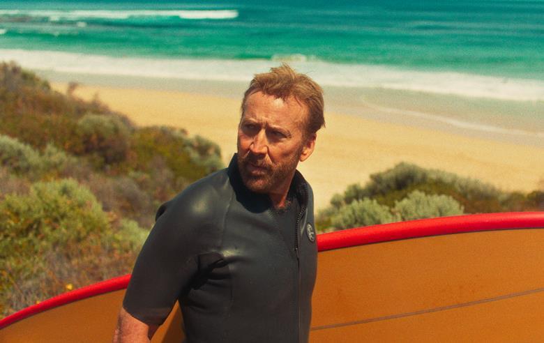 man at beach with surfboard in movie scene