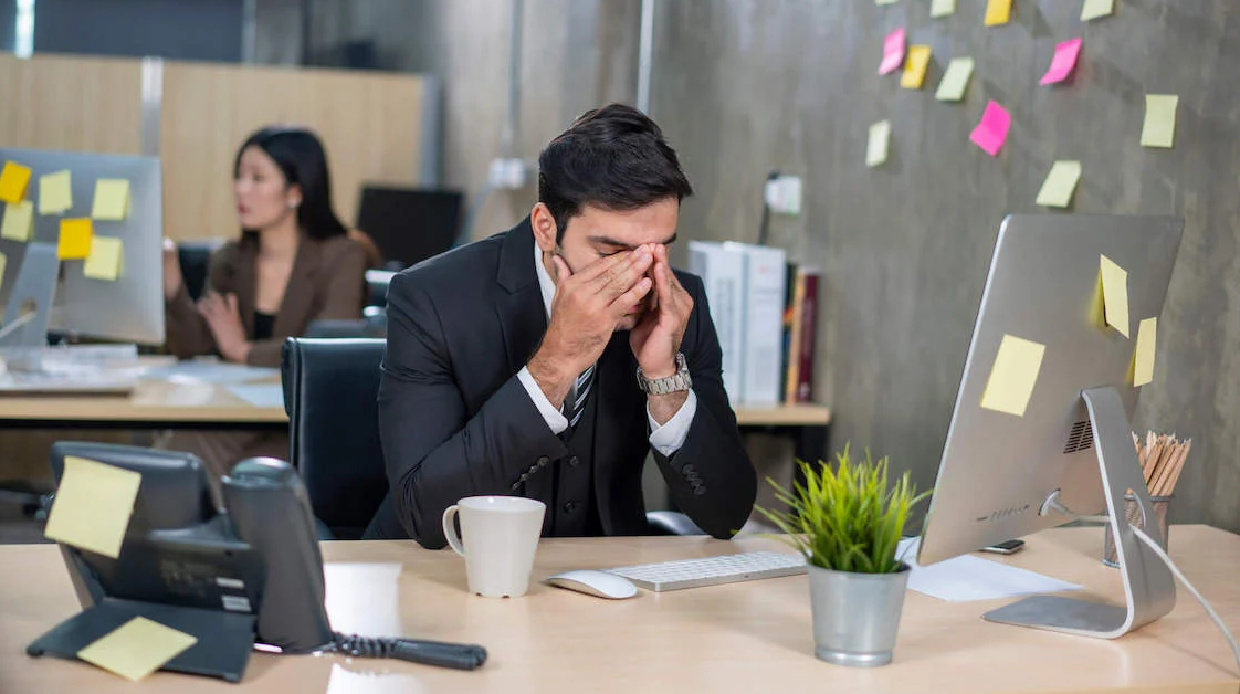 man sitting at his desk with his face in his hands