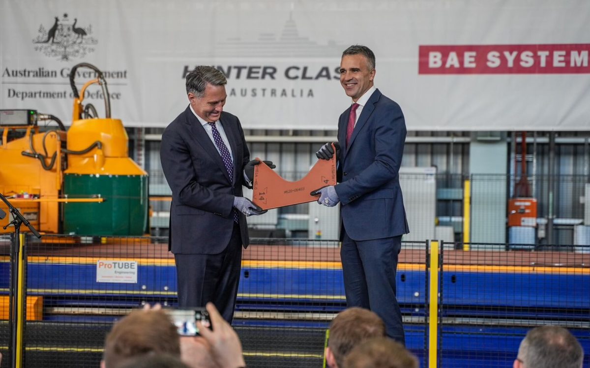 two suited men showing a ceremonial piece of steel