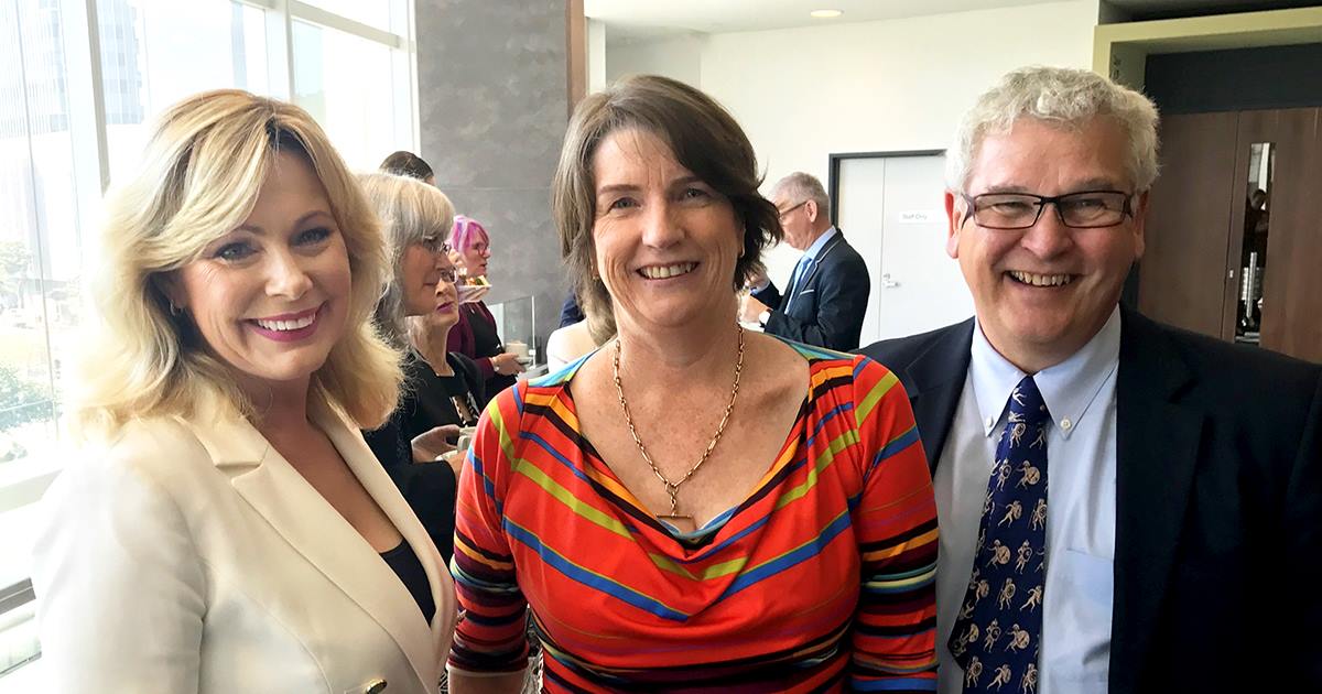 two smiling women and a man at a function