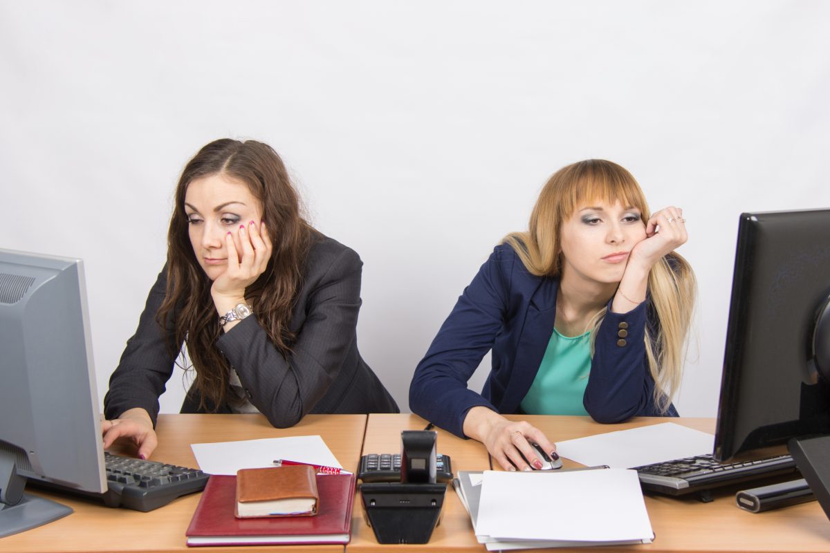 two passive-aggressive women sitting at their office desks