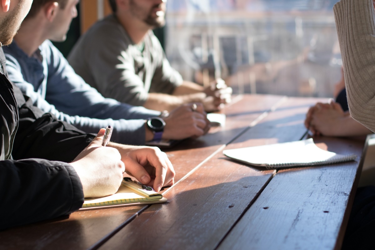 people talking and taking notes at an office table