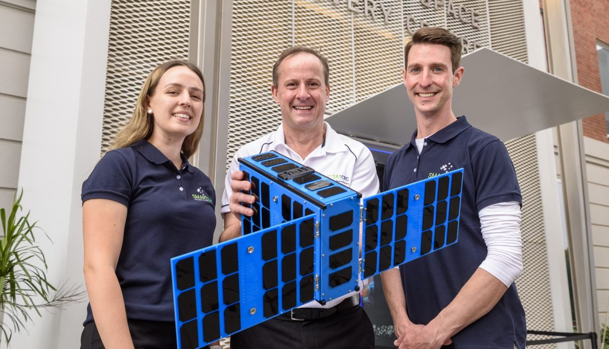 three people with a model of a satellite