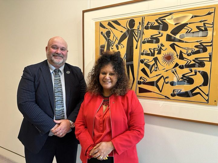 a man and a woman in front of Aboriginal artwork