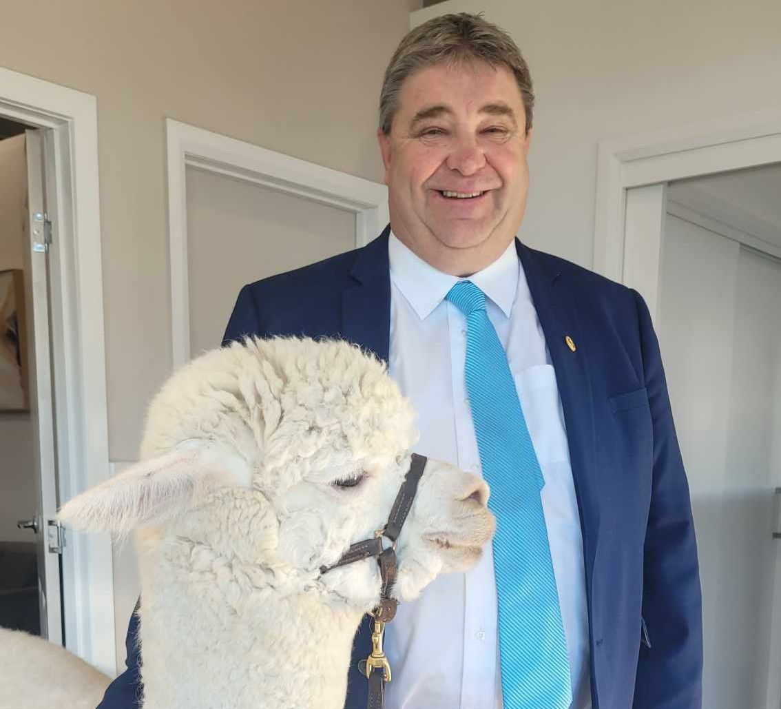 smiling man beside an alpaca