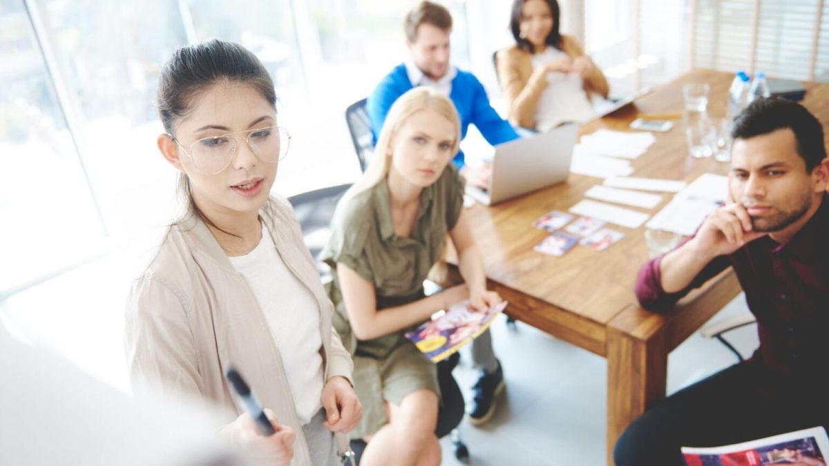 woman giving a presentation to a small group of people in an office