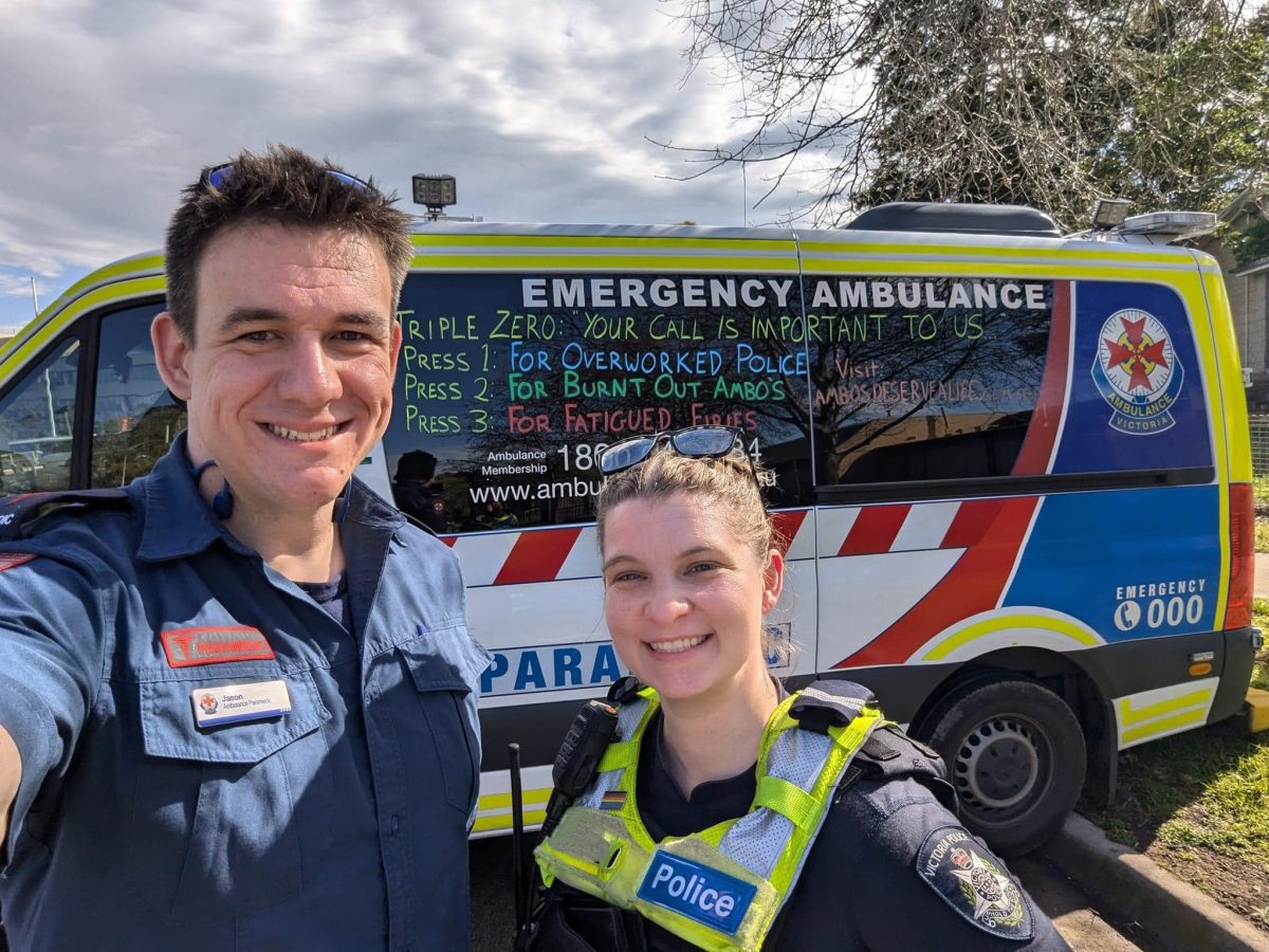 A paramedic and policewoman standing in front of an ambulance.