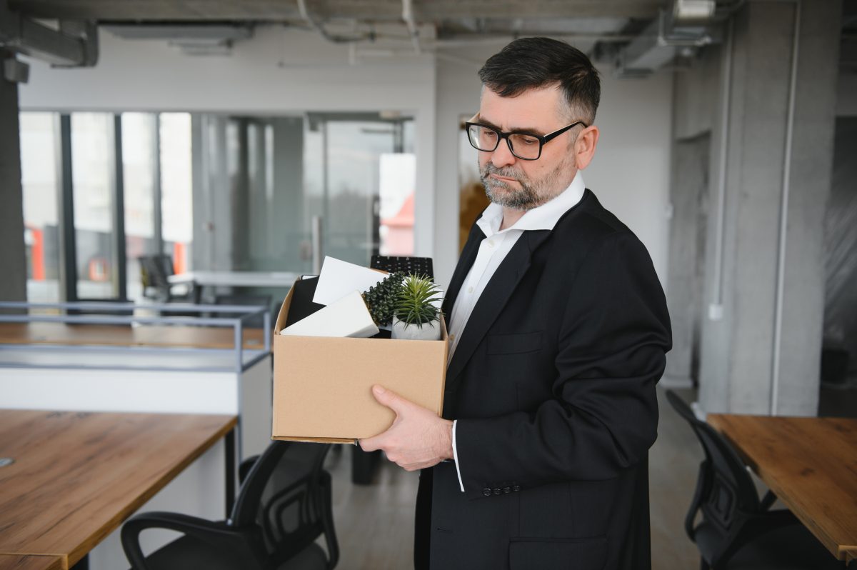 Man carrying box of personal items as he leaves his job