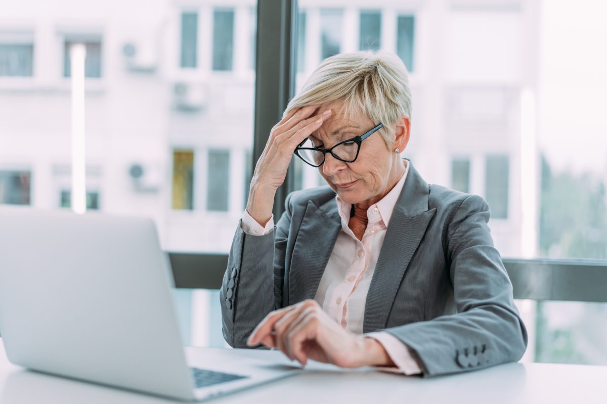 woman sitting at laptop, looking overworked