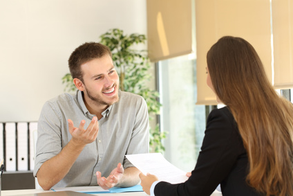 a man and a woman speaking with each other at an office desk