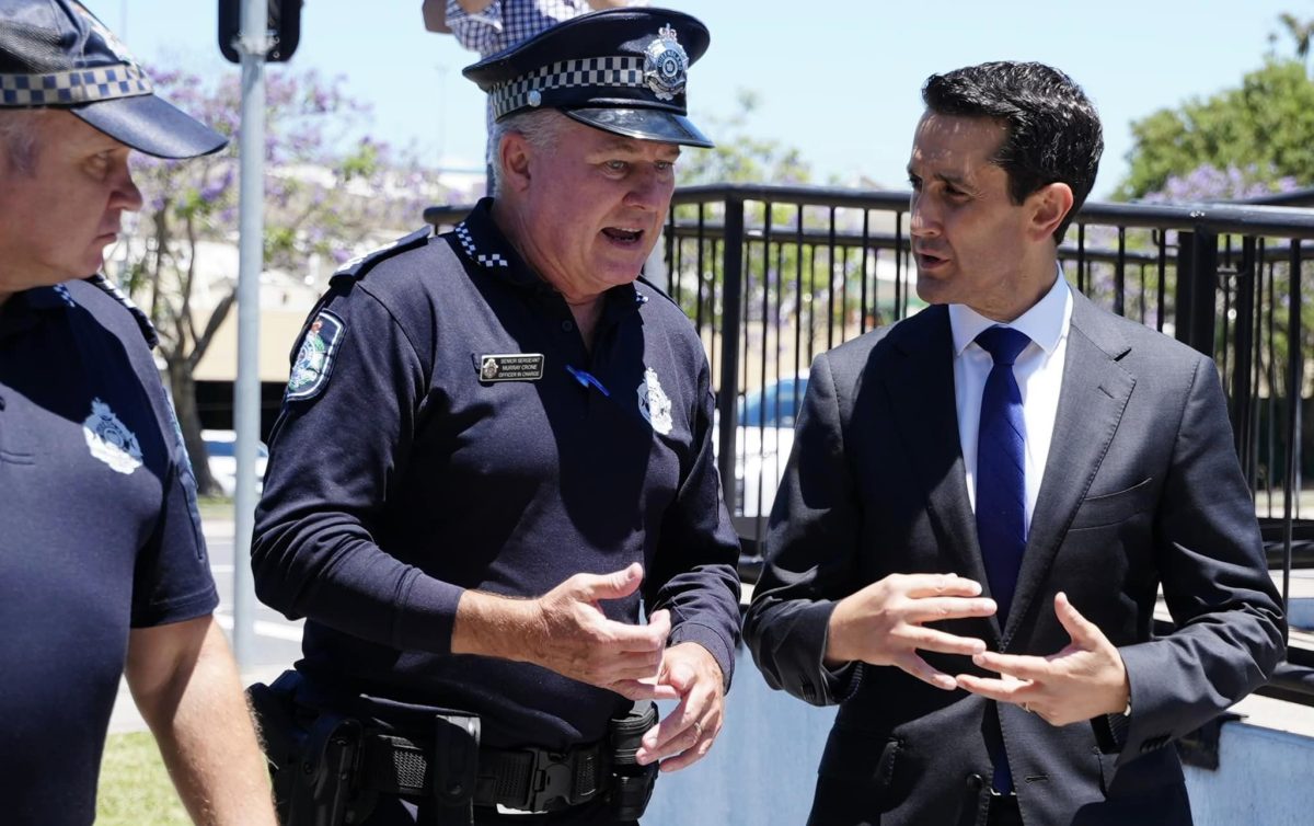 Queensland Premier David Crisafulli talking to some police while walking.