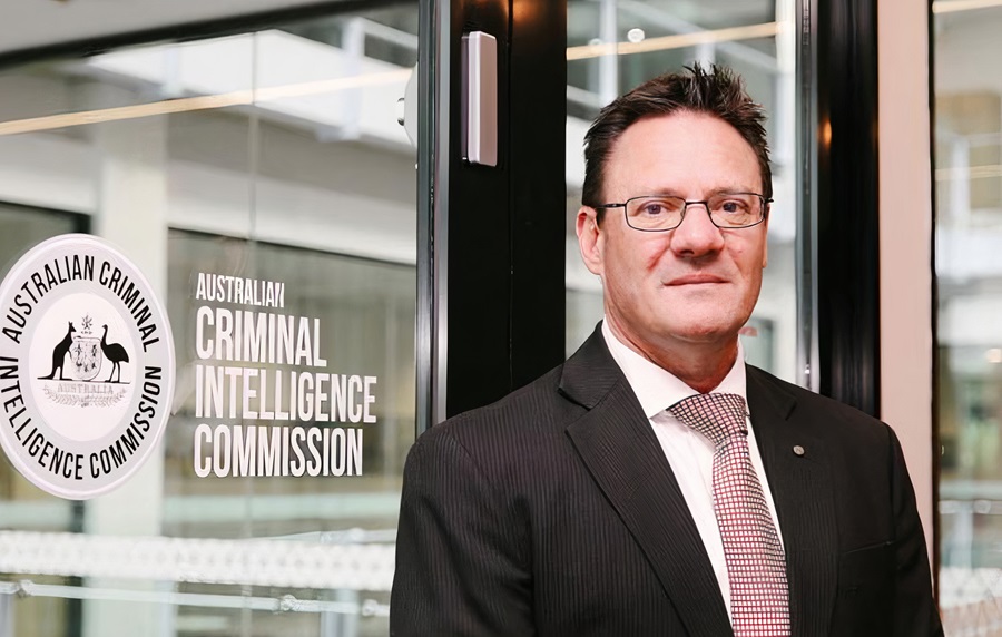 Man standing in front of a sign reading ''Australian Criminal Intelligence Commission''