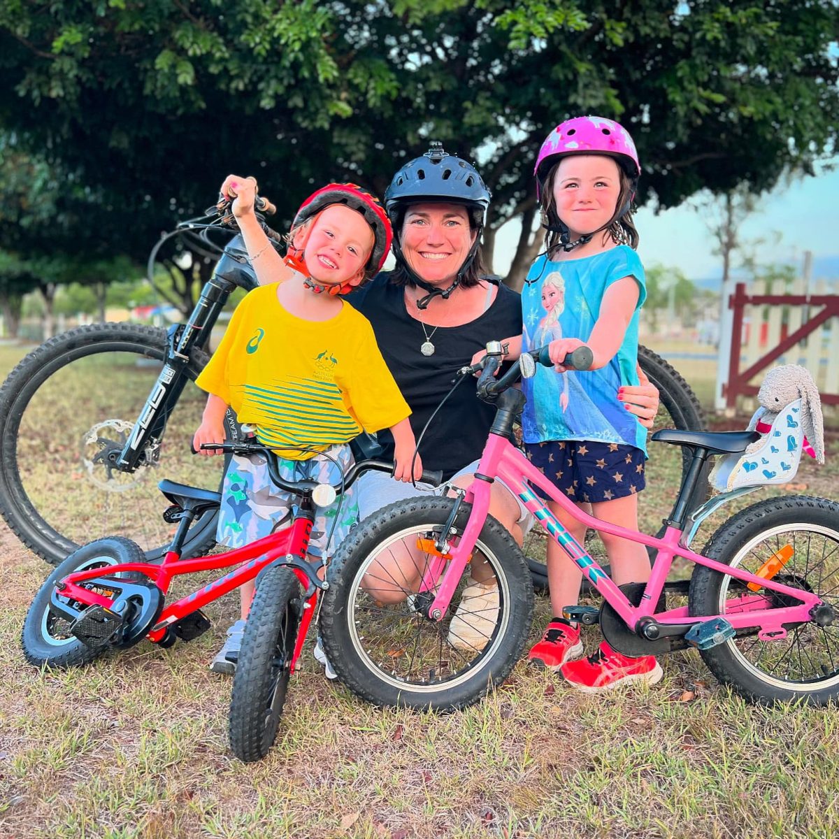 Anna Meares and her two children posing beside their bikes with helmets on.