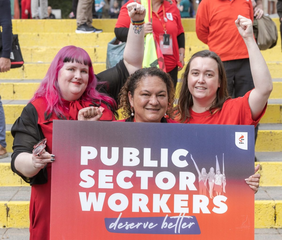 Three women holding up their fists with a sign reading: 'Public Sector Workers deserve better'.