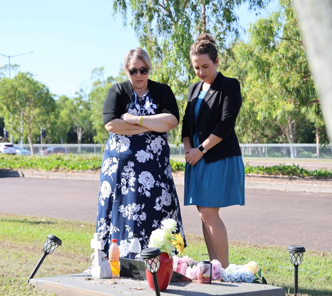 two women standing at a grave