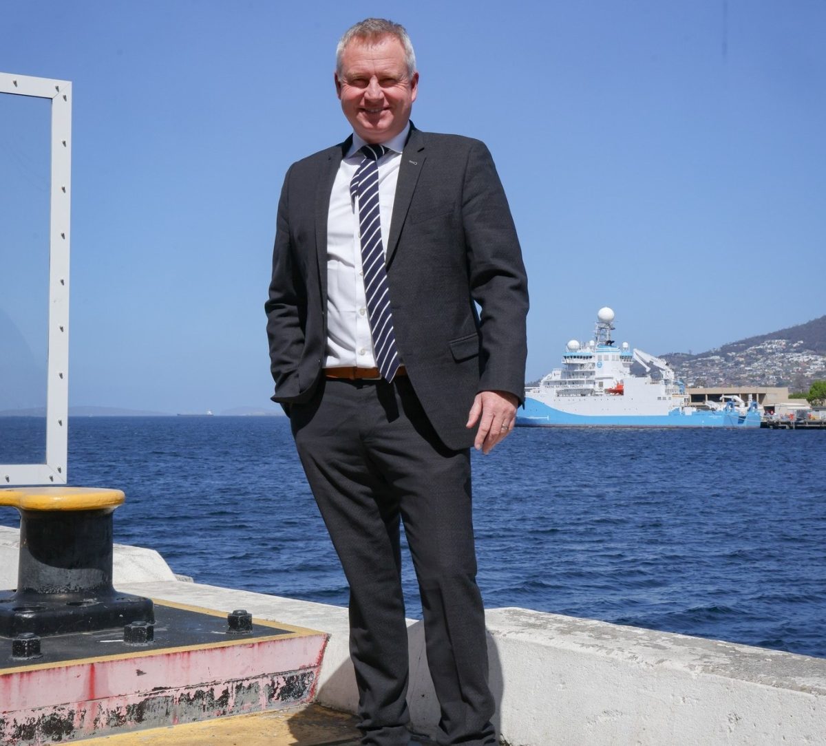 Jeremy Rockliff standing on the Hobart port with an Antarctic research ship docked in the background.