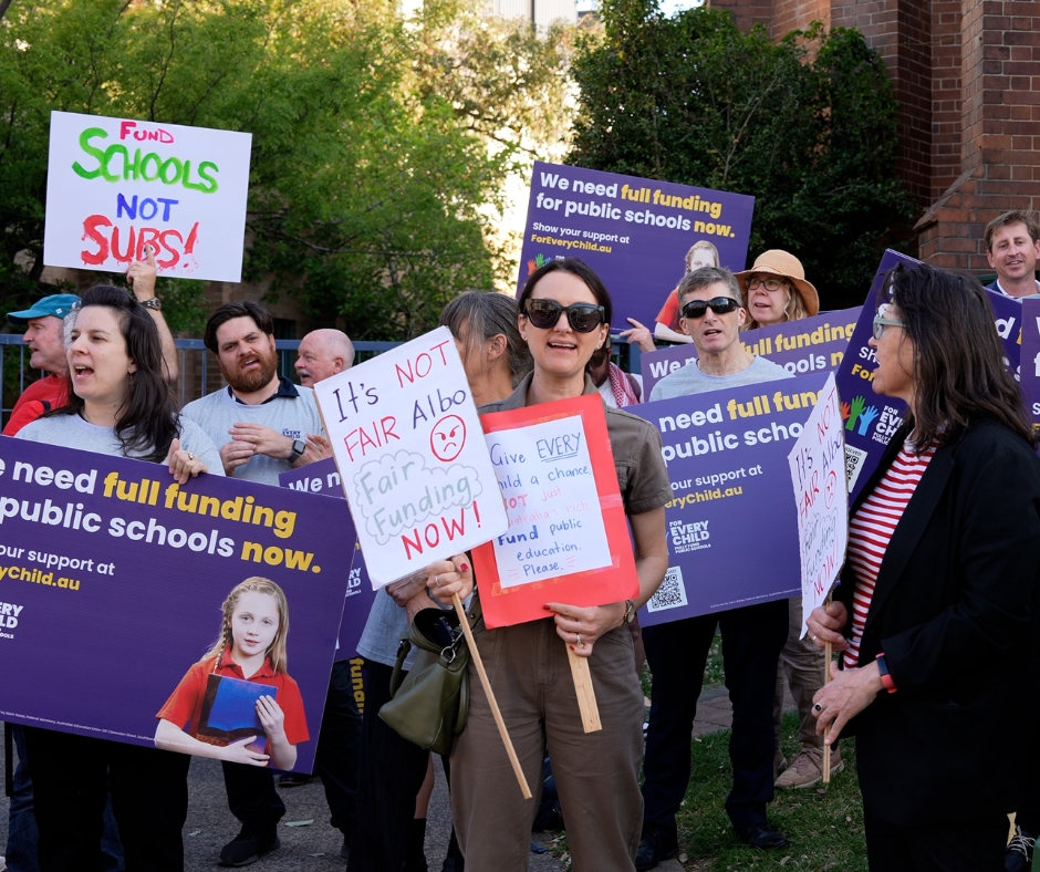 Teachers protesting with signs demanding Prime Minister Anthony Albanese fully fund NSW public schools.