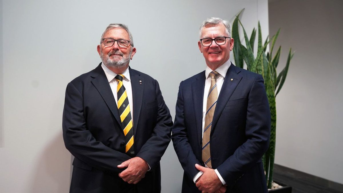 two smiling men in suits in an office 