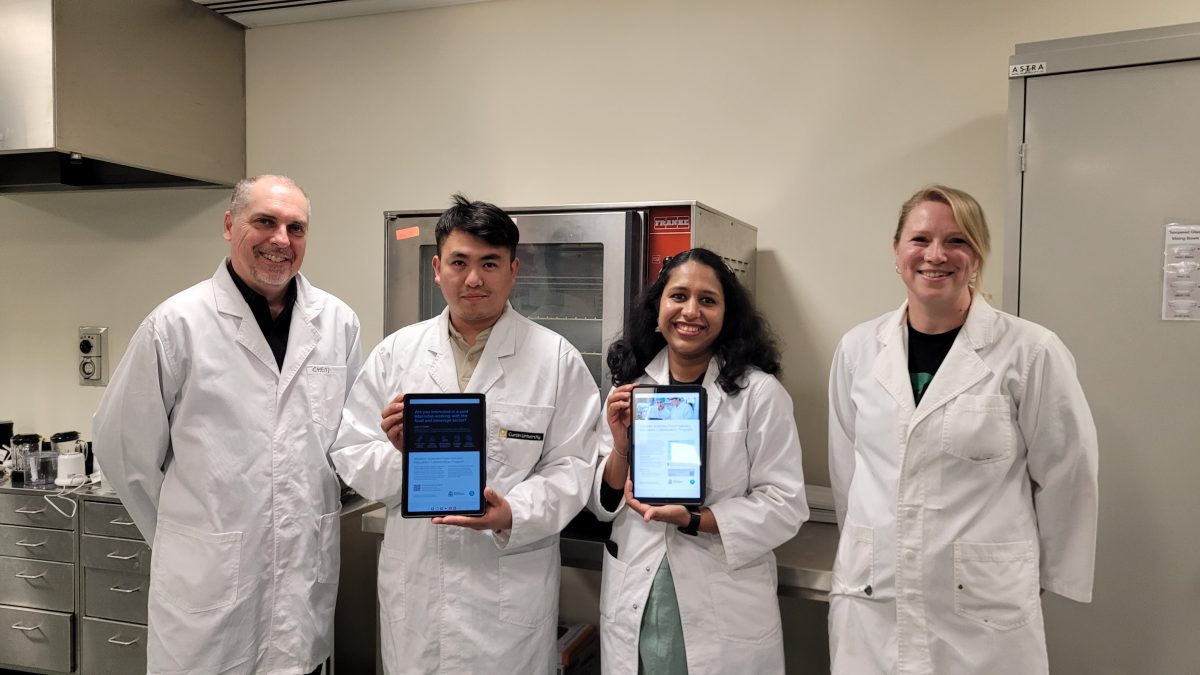 four people in lab coats and with two iPads