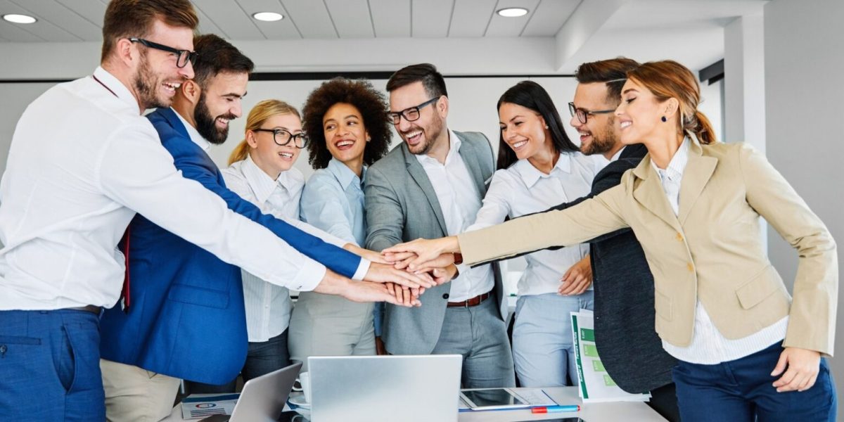 group of people joining hands in an office