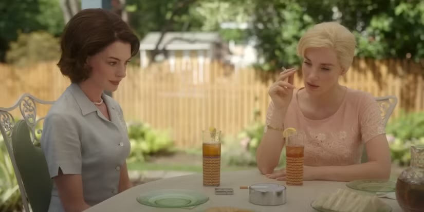 two women sitting at a table in a movie scene 