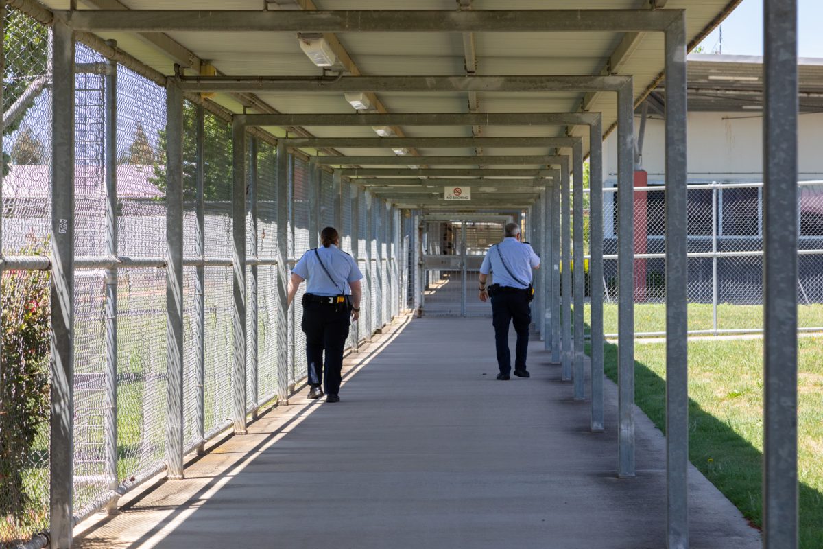 Two corrective services officers walking down outdoor corridor