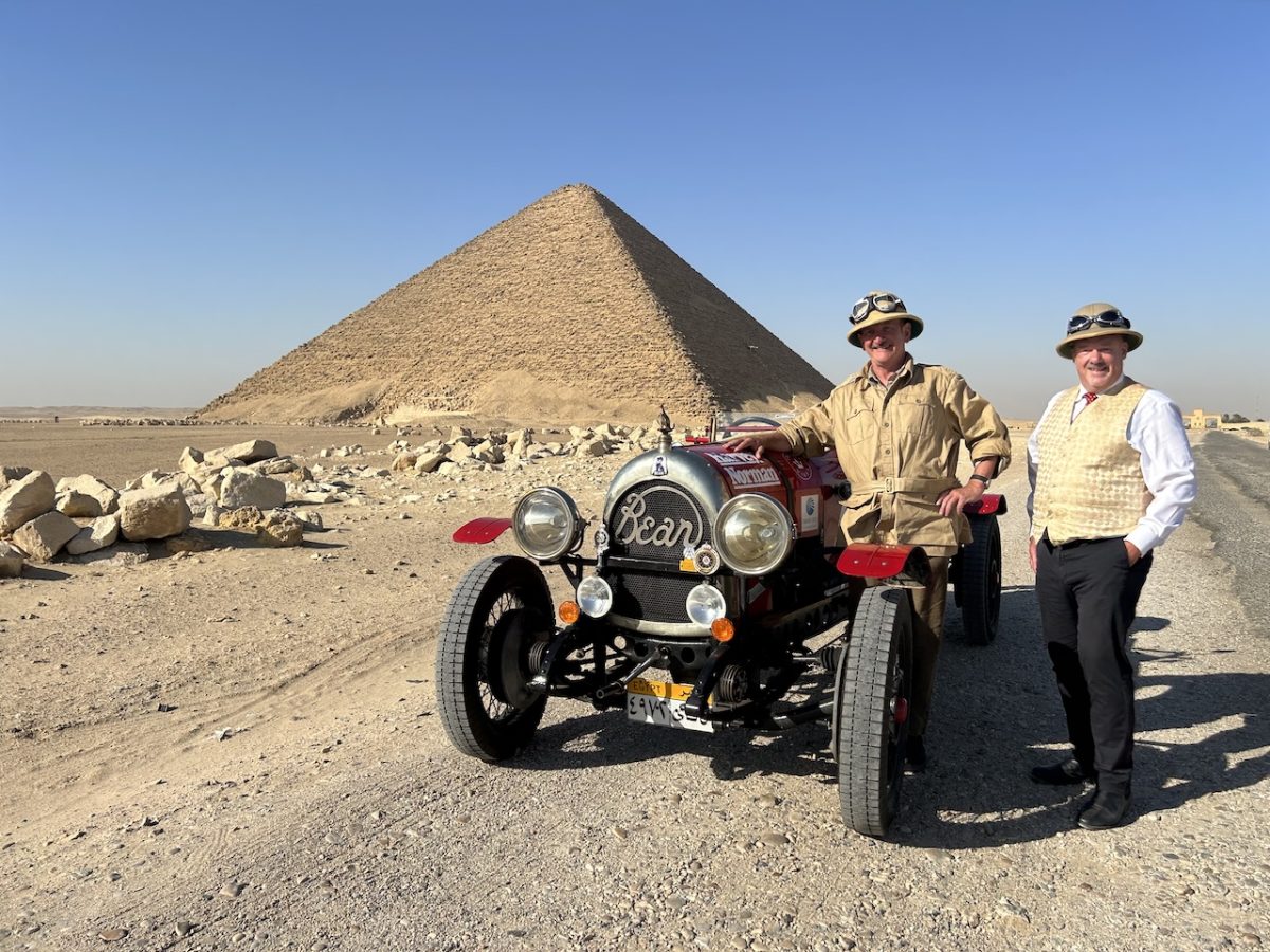 two men and an old car near a pyramid