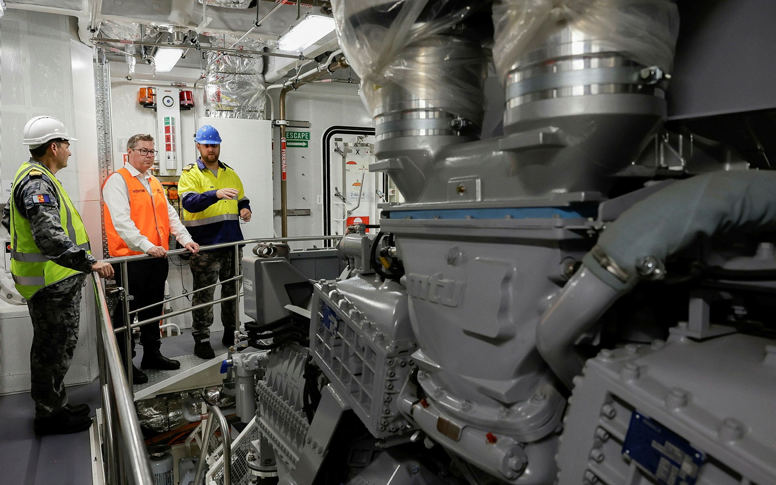 three men inspecting a navy vessel