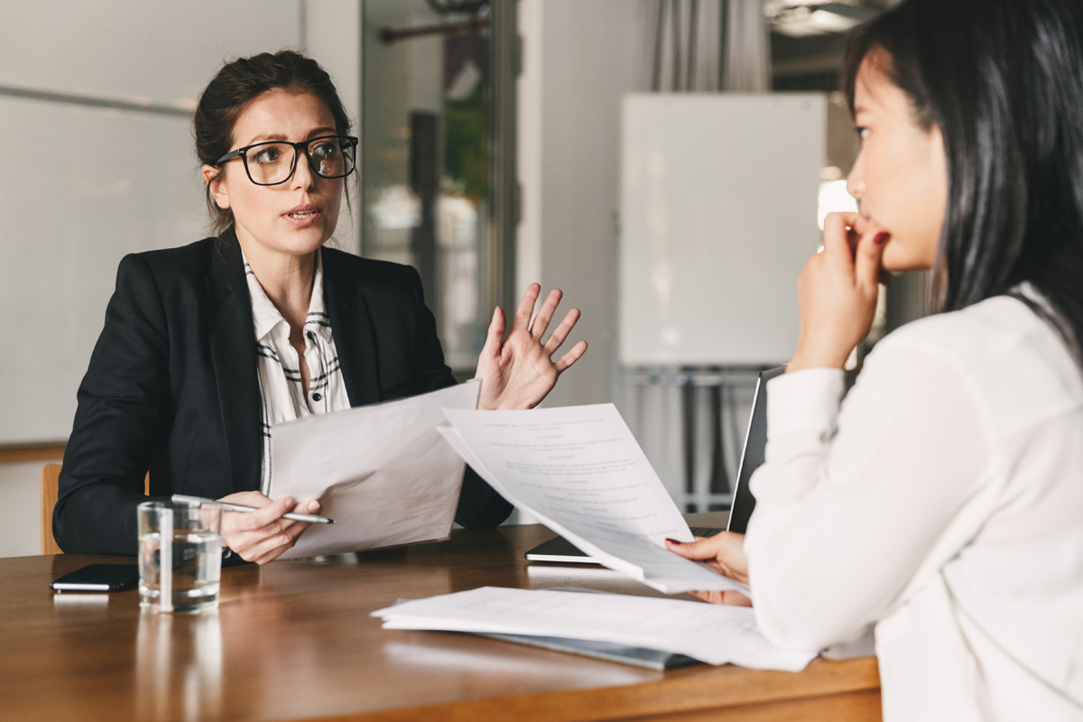 Woman in glasses talking with worried employee