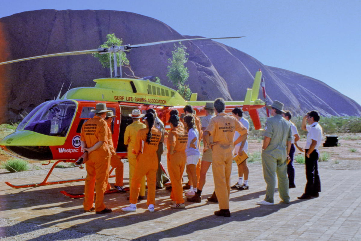 emergency service personnel standing by a helicopter while receiving a briefing 