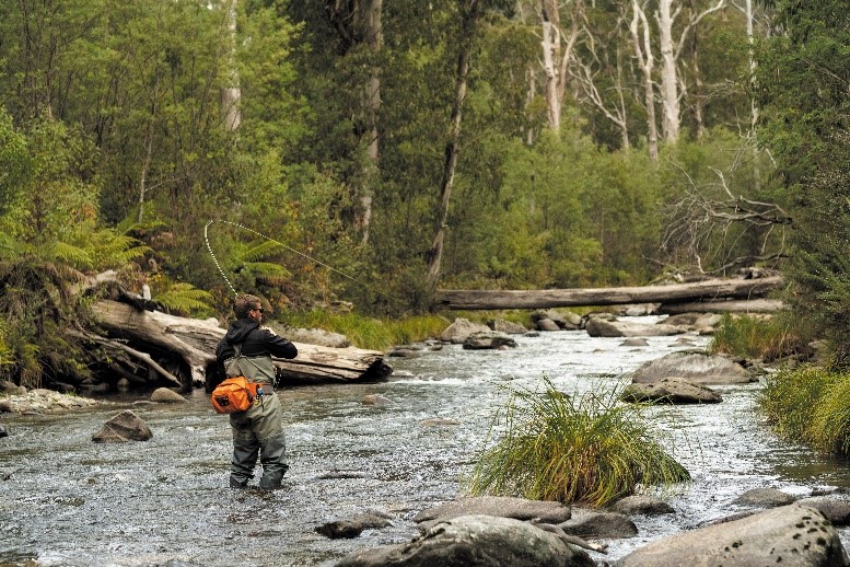 photo of a man fly fishing on a river 