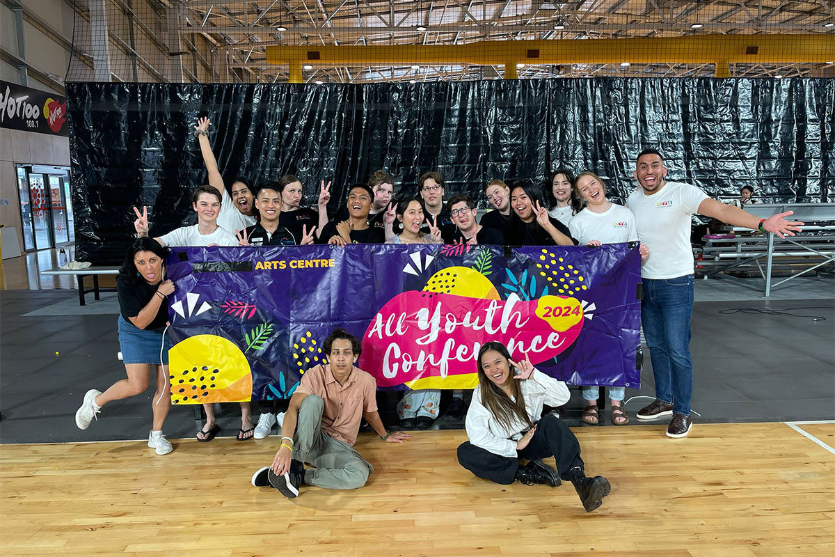 a group of young people in a hall with a banner