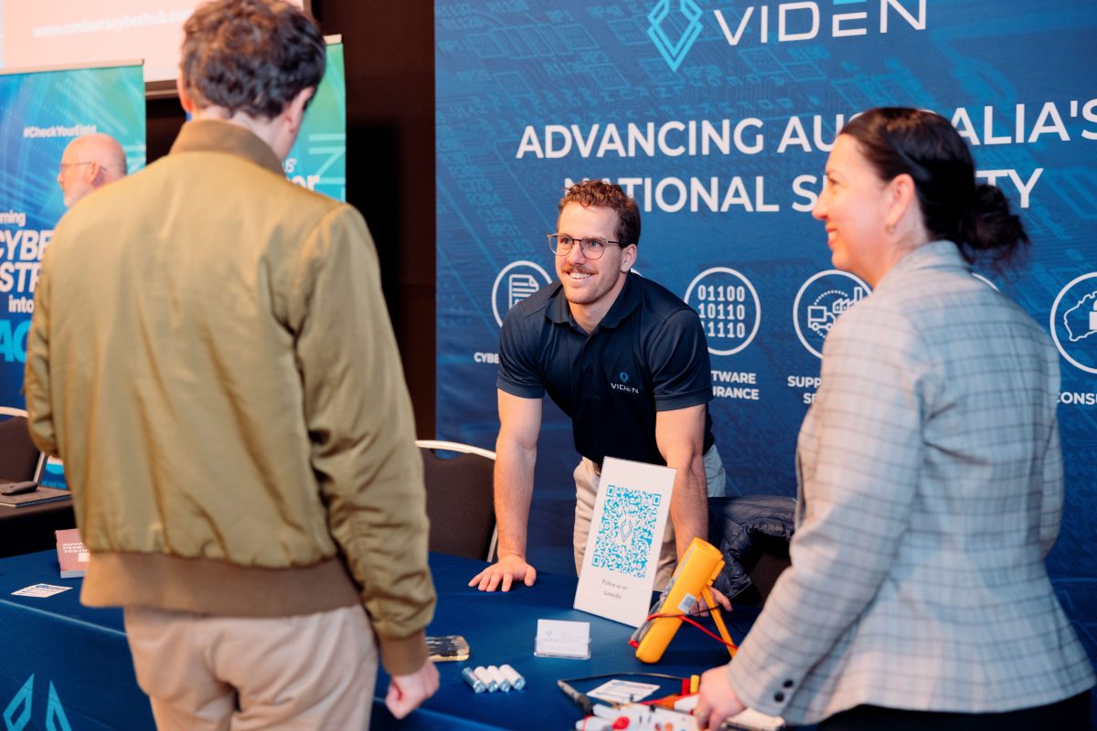 three people at an information stand at a symposium