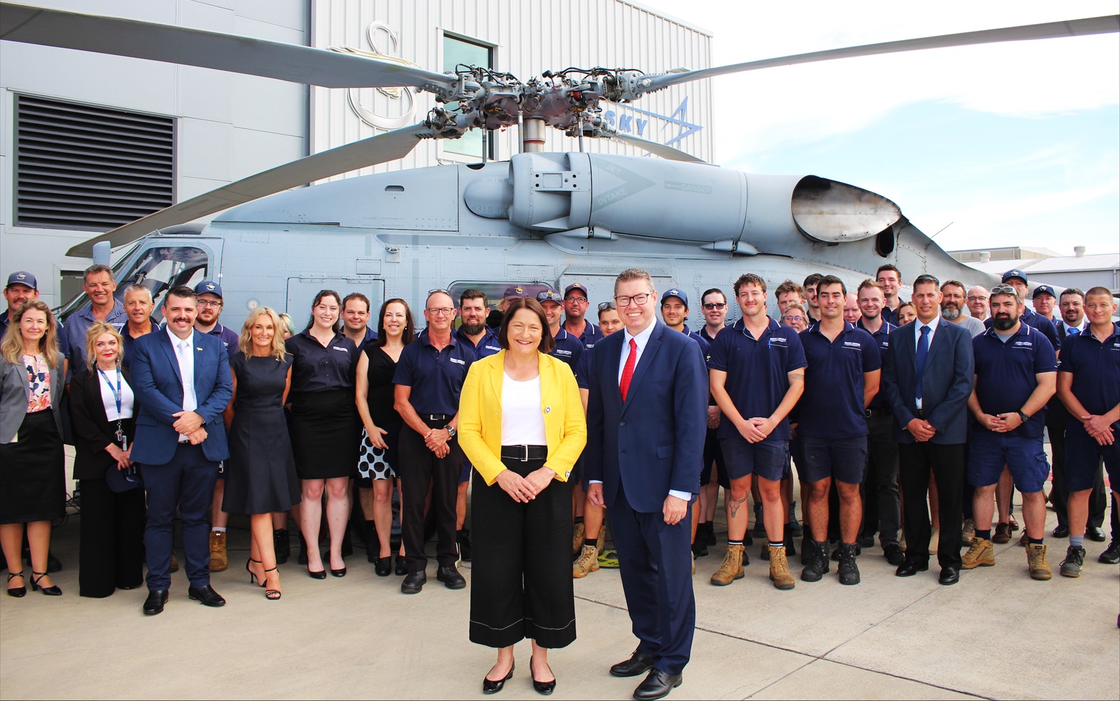 a group of people standing in front of a military helicopter