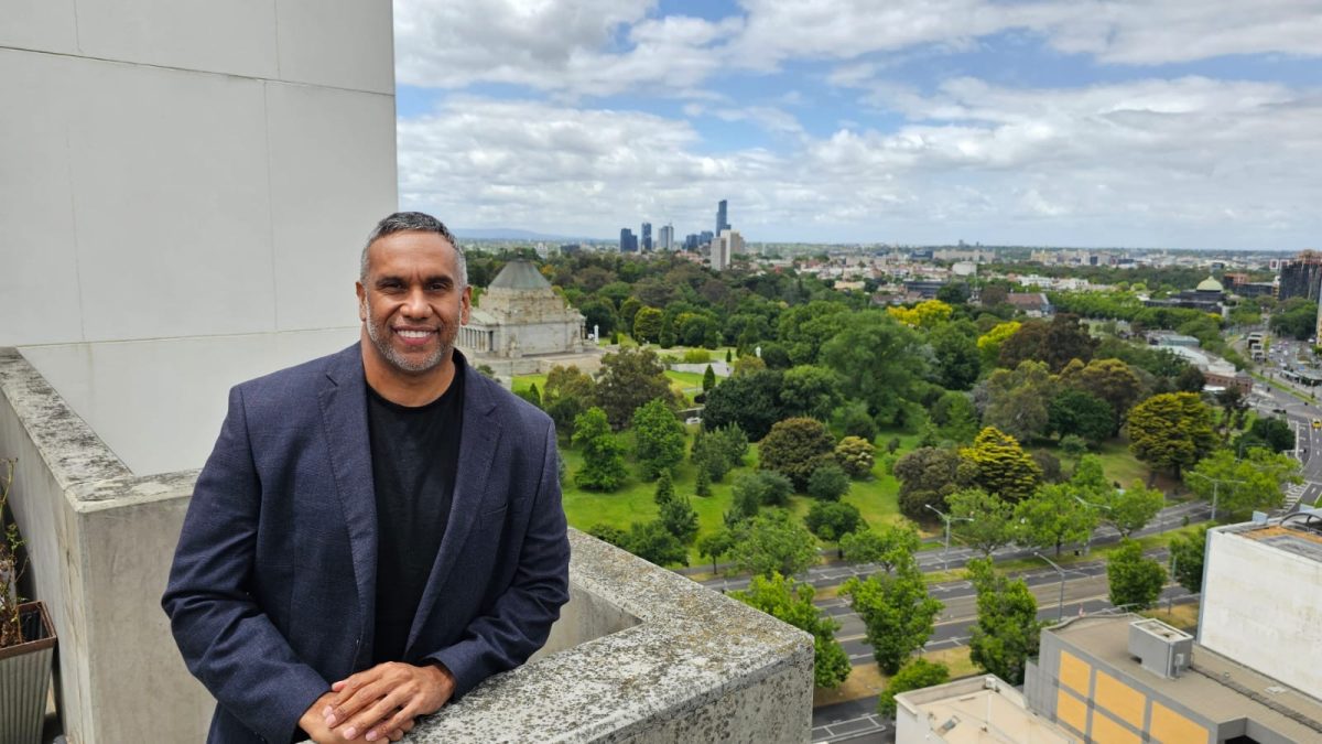 A man standing on a building's stairs, with a city in the background