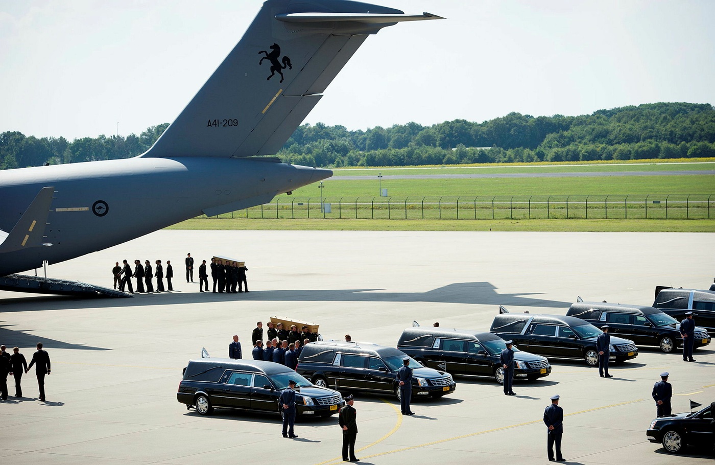 bodies being unloaded from a plane and into hearses at an airport