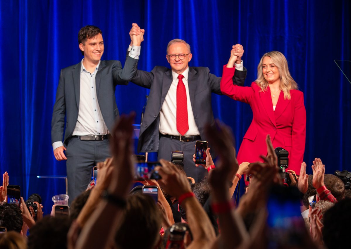 two men and a woman with their arms raised in a victory gesture
