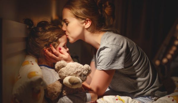 a mother kissing her young daughter on the forehead