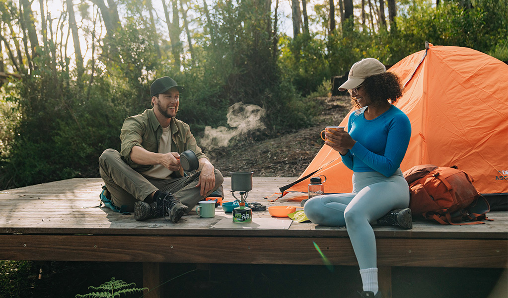 a man and a woman camping in a forest
