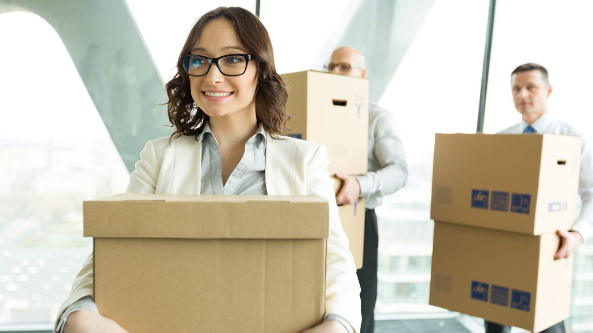 Smiling woman leaving office and carrying a box