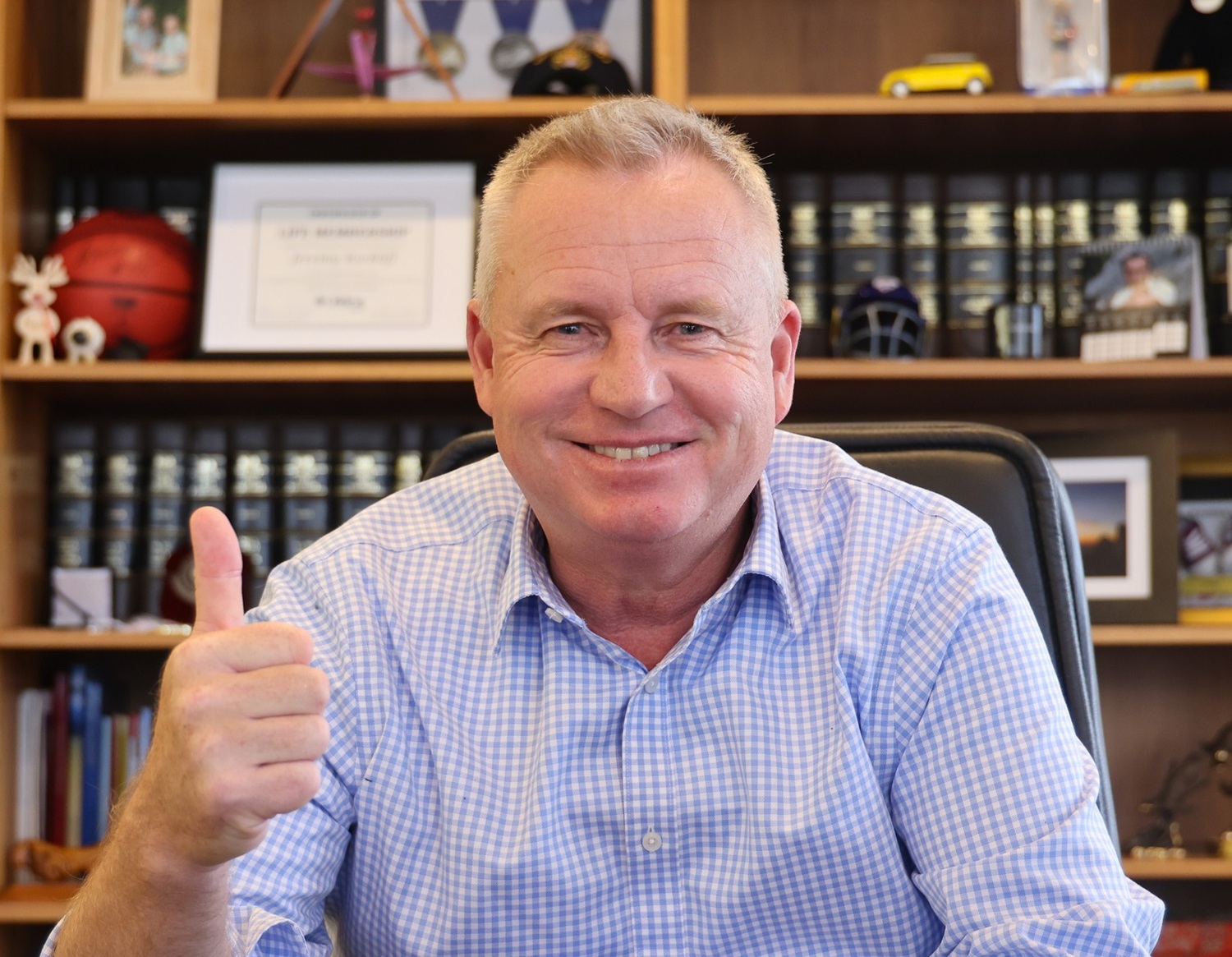 man sitting at his desk and giving the thumps-up