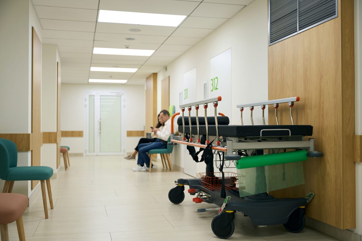 hospital corridor with a gurney and two people seated