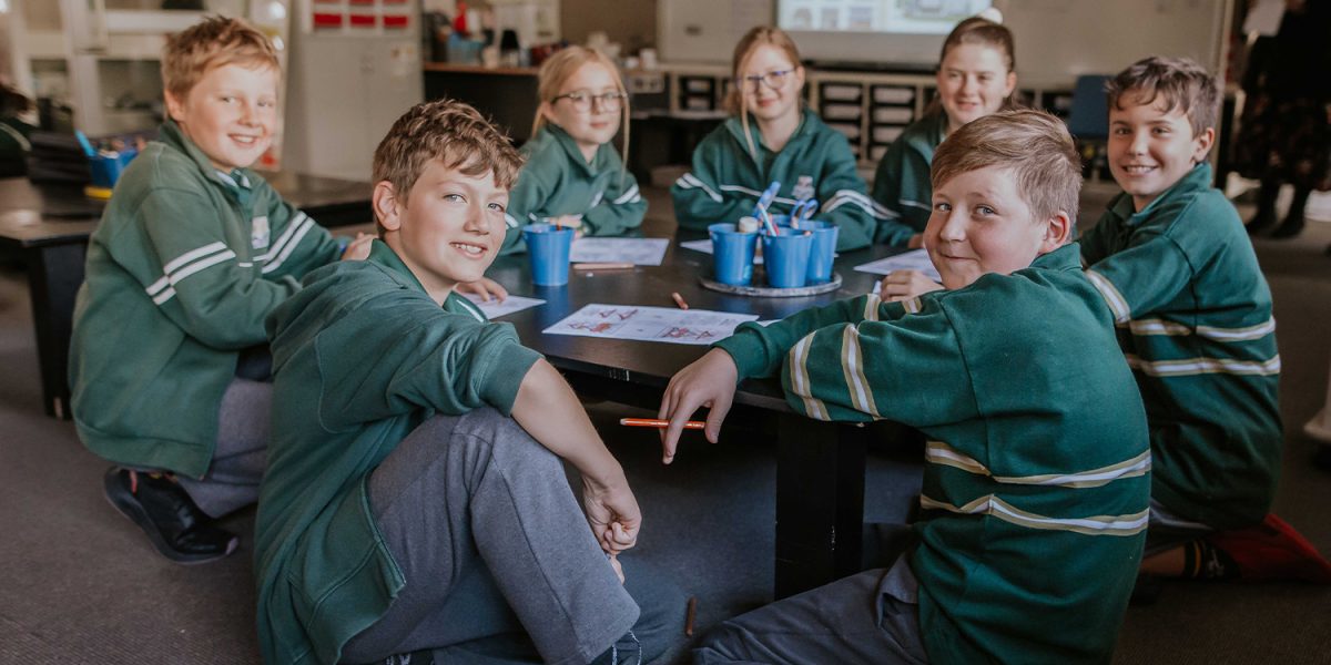 schoolkids sitting around a table in class