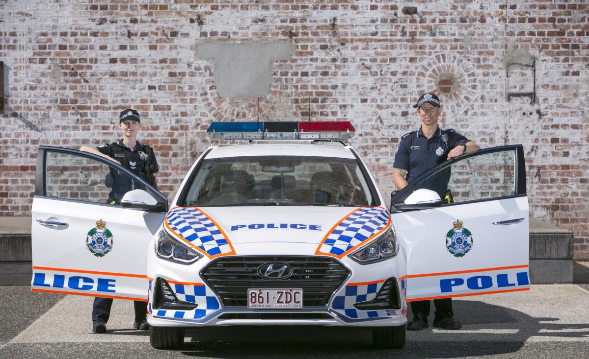 two Queensland police officers and a police car