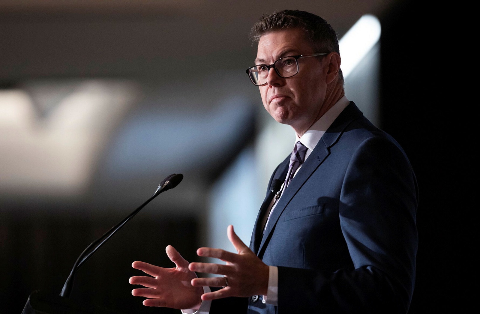 man in a suit addressing a crowd at a lectern