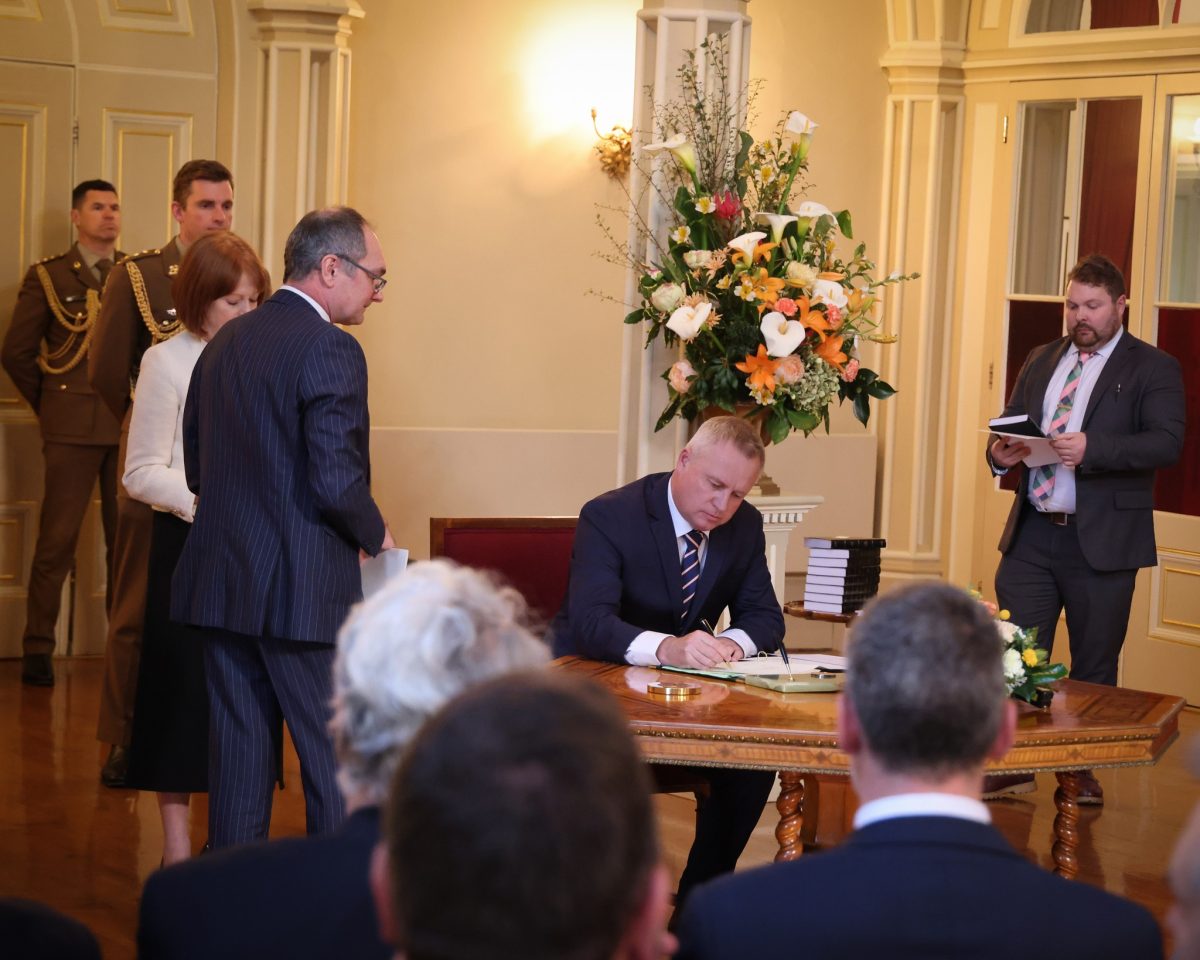 man signing a document during an official swearing-in ceremony