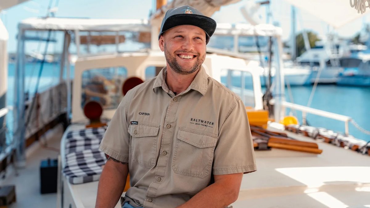 smiling young man sitting in a boat at a marina
